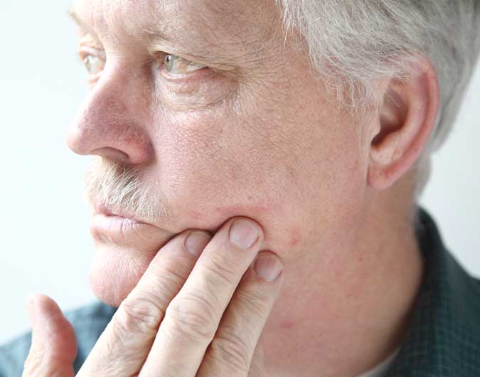 psoriasis ratgeber alltag schuebe vorbeugen senior reibt sich die wange